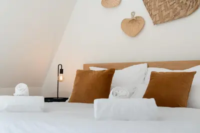 a bedroom with a white bed with brown pillows at Saint Pablo Boutique Apt I 3BR, Grote Markt, City Center, Near Station in Hasselt