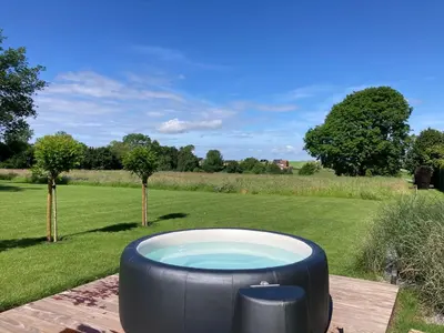 a large bath tub sitting on top of a wooden deck at Cour 44 - Gite de charme avec sauna et jacuzzi in Remicourt