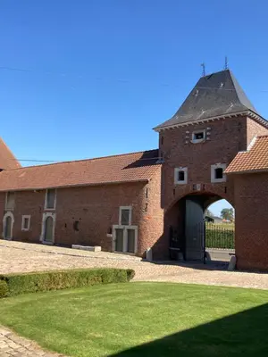 a red brick building with a gate and an archway at Cour 44 - Gite de charme avec sauna et jacuzzi in Remicourt