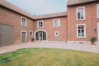 a brick house with a large yard in front of it at Cour 44 - Gite de charme avec sauna et jacuzzi in Remicourt