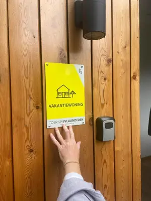 a man is unlocking a door with a sign on it at Vakantiewoning Mystiek in Zutendaal