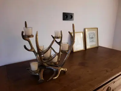 a antler candle holder with three candles on a table at Ô Colombages in Les Biolles