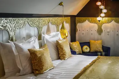 a bedroom with a bed with white and gold pillows at B&B 1001 nacht in Zonhoven