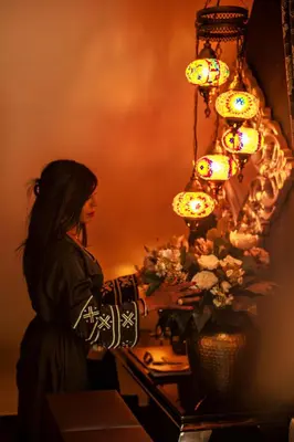 a woman standing at a table with flowers and lights at B&B 1001 nacht in Zonhoven