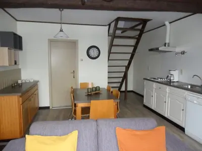 a living room with a couch and a table and a kitchen at Schophemmerhoeve in Voeren