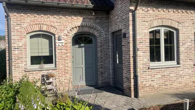 a brick building with a door and two windows at Vakantiewoning - ‘t Ouwershuys in Opoeteren
