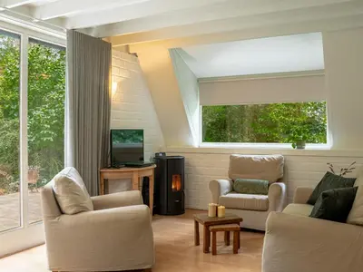 a living room with two chairs and a television at Boshuisje Rekem - Boris in Lanaken