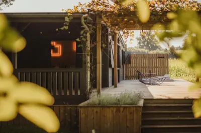 a bench sitting on a deck in front of a house at Ô NaNo Glamping in Dalhem