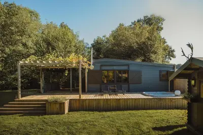 a tiny house with a deck and a hot tub at Ô NaNo Glamping in Dalhem