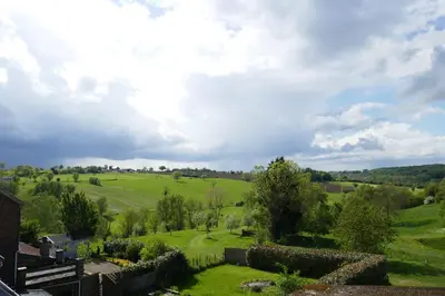 a view of a green field with trees and houses at B&B La ferme de Berwausault in Herve