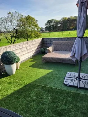 a patio with a couch and an umbrella on the grass at Welness gastenverblijf Carpe Diem in Oudsbergen