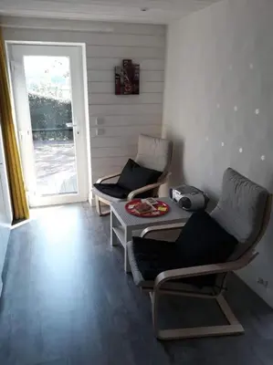 a room with two chairs and a table and a door at Studio Au jardin fleuri in Verviers