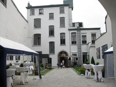 a white building with tables and chairs in front of it at B&B N°5 in Liège