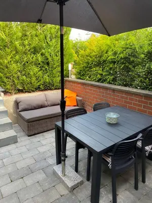a wooden table with an umbrella on a patio at bij Petros in Oudsbergen