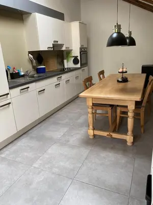 a kitchen with white cabinets and a wooden table at bij Petros in Oudsbergen
