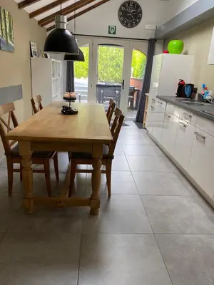 a kitchen and dining room with a wooden table and chairs at bij Petros in Oudsbergen