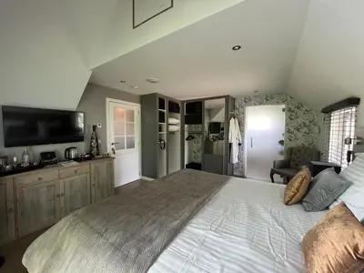 a large bedroom with a large bed and a television at Bed & Bokes aan de Maaskant in Lanaken