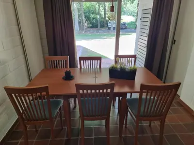 a dining room table and chairs with a large window at Gezellig appartement in groene omgeving in Drijhoeven