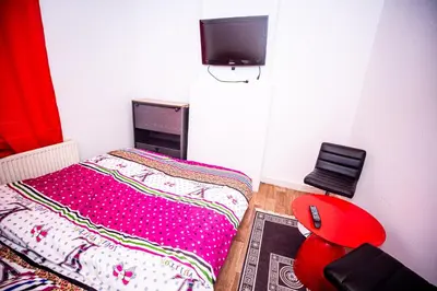 a small bedroom with a bed and a red chair at Superbe chambre sur liège in Liège