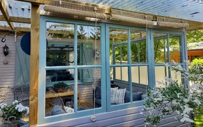 a screened porch with blue windows on a house at Isidaura in Zutendaal