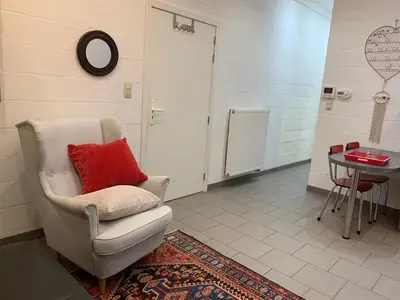 a room with a chair with a red pillow and a table at Le Pavillon de Flore by Maison Brasseurs d'Etoiles - Appartement 2 personnes in Liège