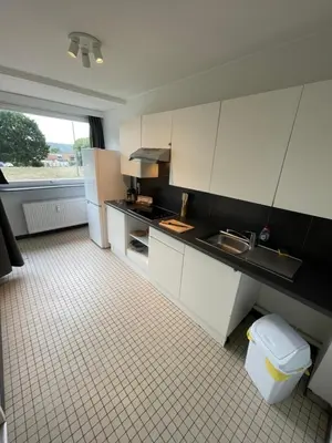 a kitchen with white cabinets and a tile floor at Alexis's loft in Liège