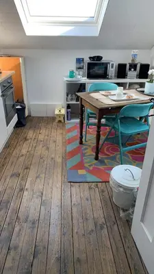 a room with a table and chairs and a kitchen at Les chineurs du 81 in Liège