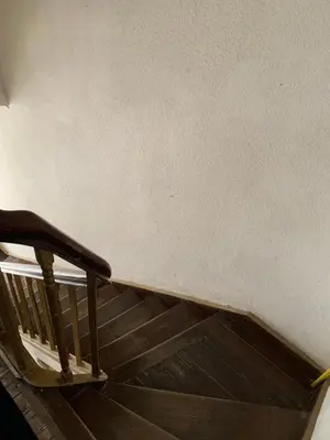 a stairway with a wooden rail and a white wall at Les chineurs du 81 in Liège