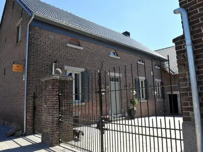 a brick building with a fence in front of it at Vlaanderen Cozy Cottage in Eisden