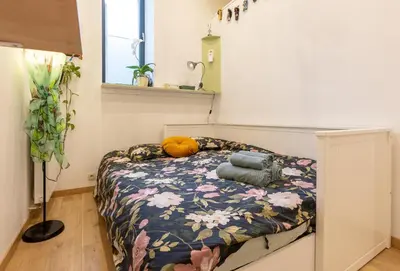 a bedroom with a bed with a flower patterned blanket at La Chambre Suspendue by Maison Brasseurs d'Etoiles - Appartement 2 personnes in Liège
