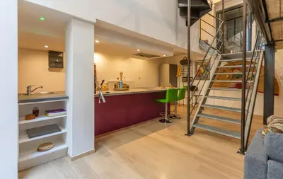a room with a kitchen and a staircase in a loft at Le Loft Nautilus by Maison Brasseurs d'Etoiles in Liège