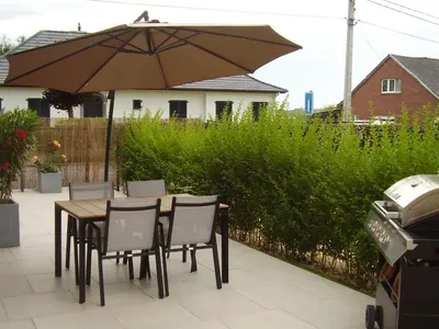 a wooden table with chairs and an umbrella at lit-loo in Hasselt