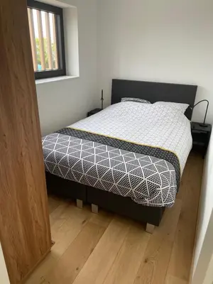 a bedroom with a bed and a wooden floor at Tiny house moderne in Thimister