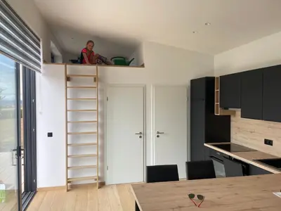 a person sitting on a loft bed in a kitchen at Tiny house moderne in Thimister