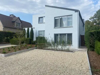 a white house with a garden in front of it at Route 123 Birchwood Pension in Kortessem