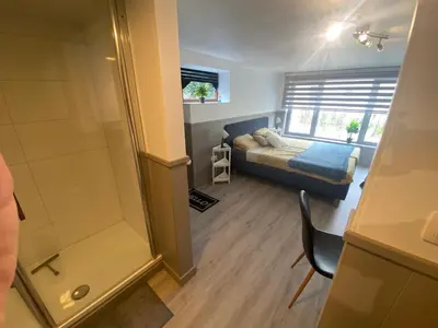 a small bedroom with a bed and a shower at Route 123 Birchwood Pension in Kortessem