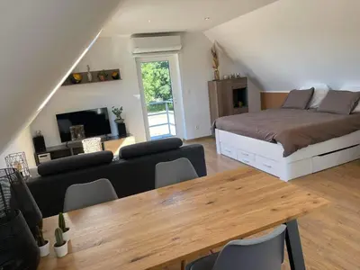 a bedroom with a bed and a living room with a table at Au cœur de l'Ardenne Bleue - Studio avec piscine in Baelen