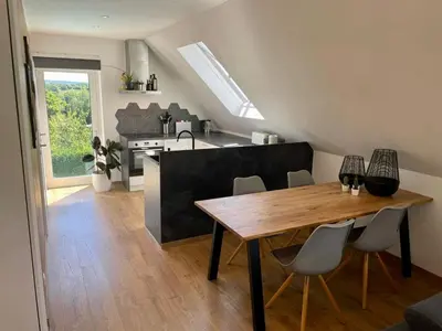 a kitchen and dining room with a wooden table and chairs at Au cœur de l'Ardenne Bleue - Studio avec piscine in Baelen