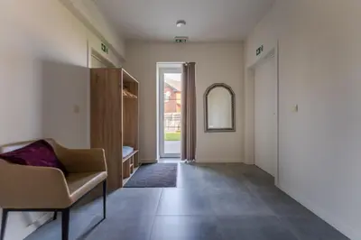 a living room with a chair and a mirror at De Hoog Velden 11 in Pelt