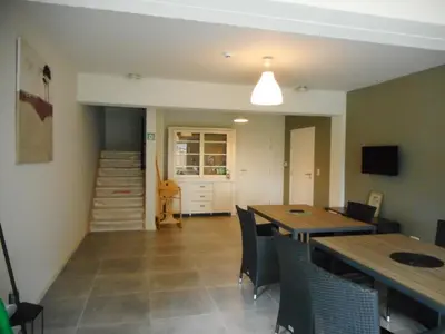 a dining room with tables and chairs and a staircase at De Hoog Velden 11 in Pelt