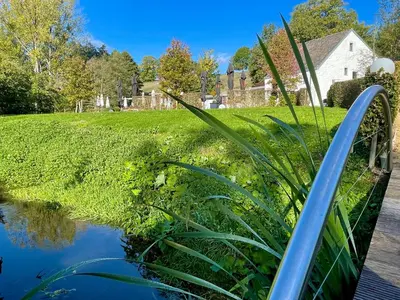 a pond with a blue rail next to a yard at La Bel échappée in Aubel