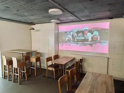 a dining room with tables and chairs and a screen at La Bel échappée in Aubel
