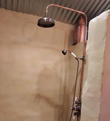 a shower with a light on the side of a wall at La Cabane du Coing in Visé