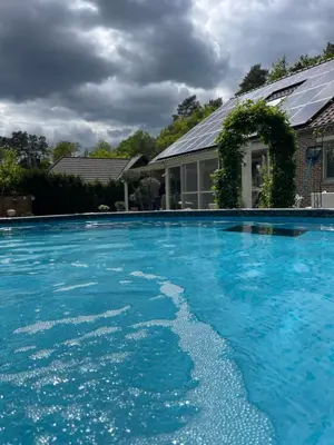 a large blue swimming pool in front of a house at Huys In As in As