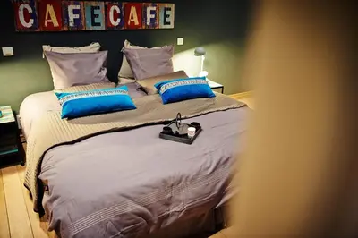 a bedroom with a bed with blue and gray pillows at B&B Au Clair Obscur in Verviers