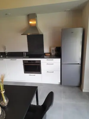 a kitchen with white cabinets and a refrigerator at De Hoog Velden 13 in Pelt