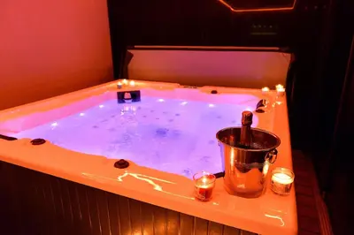 a hot tub with a bucket and candles in it at SuiteDreams - Sky Suite - Liège in Liège