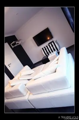 a living room with a white couch and a tv at V E R O N E - Rooms & Suites - Liège - Rocourt in Liège