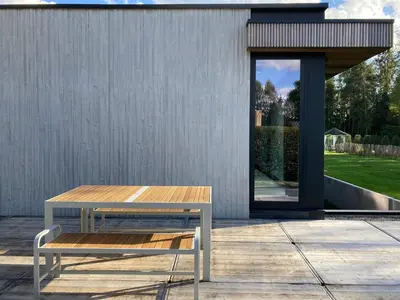 a wooden table and a bench on a patio at Shelter in Zutendaal