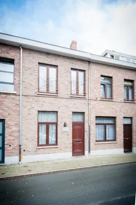 a brick building with red doors on a street at Holiday Home 't Regulierenhuisje in Tongeren